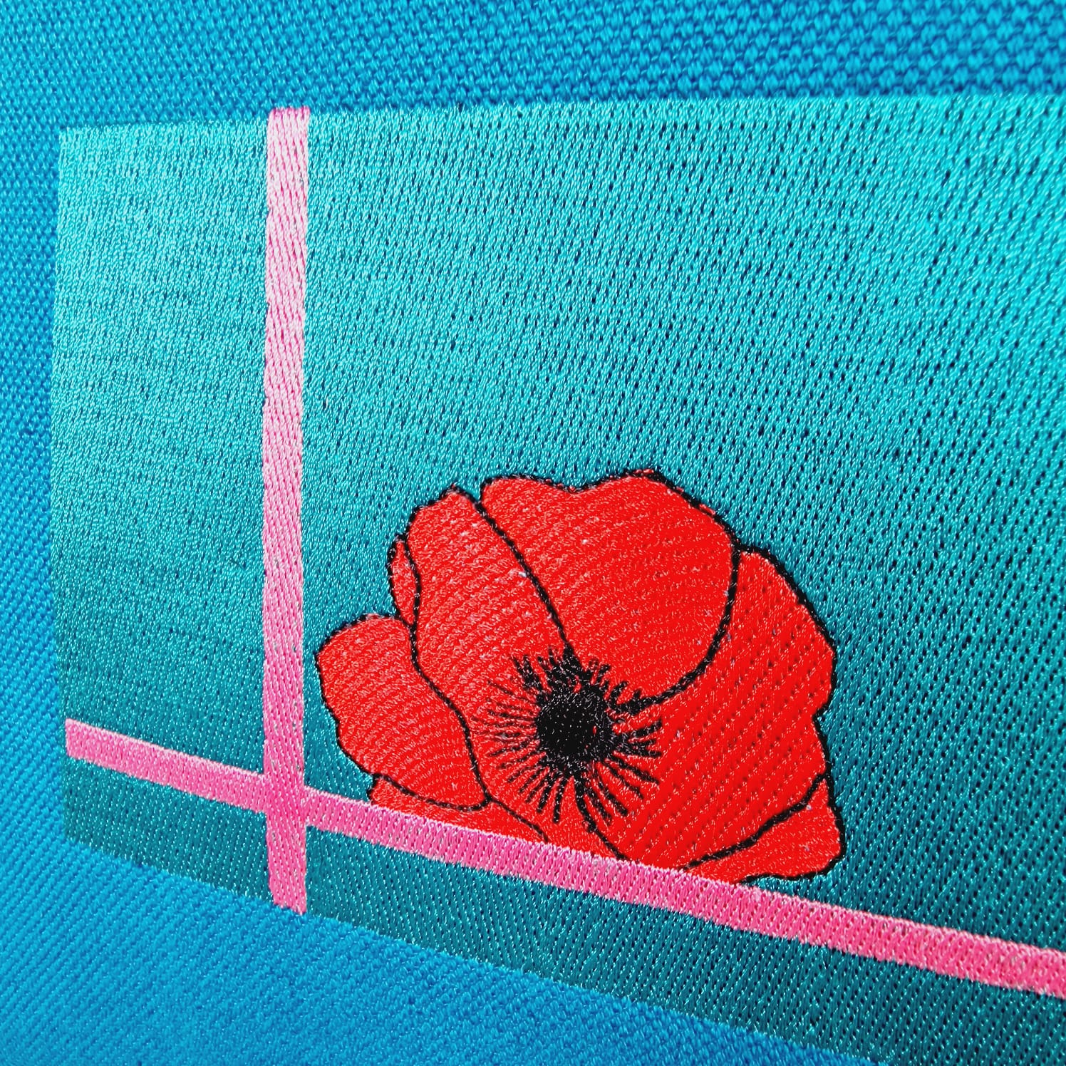 Close-up of embroidered red poppy on blue linen and cotton handbag with purple leather handles