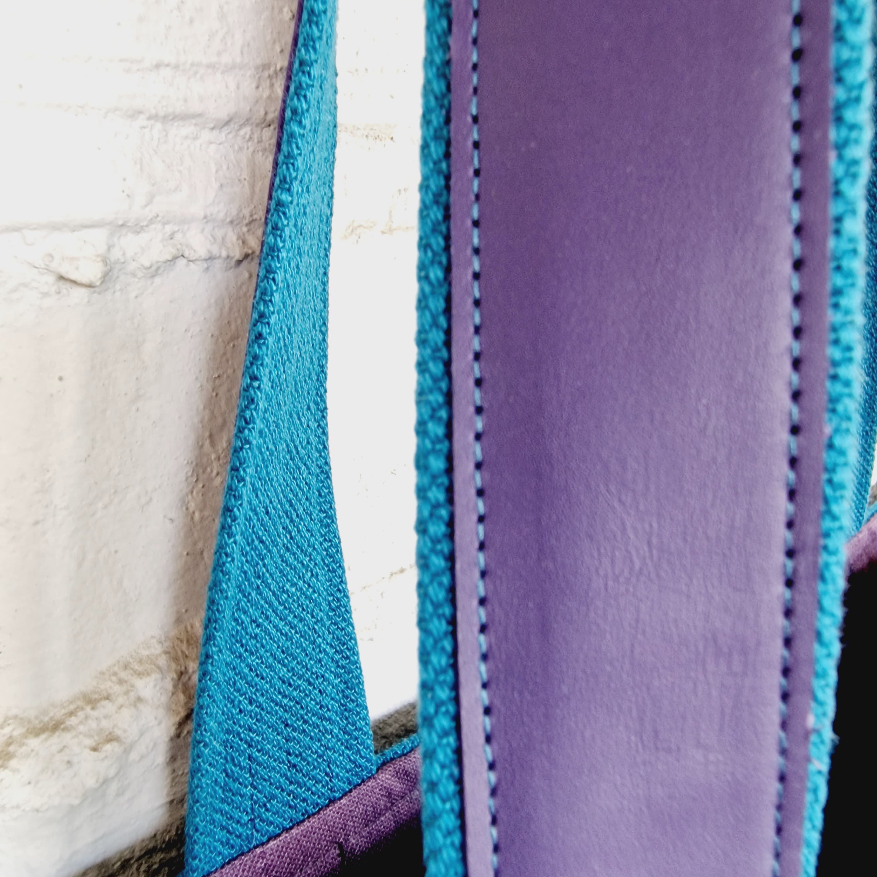 Detailed view of purple leather handle reinforcement on blue linen handbag