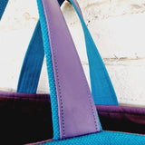 Detailed view of purple leather handle reinforcement on blue linen handbag and purple inside