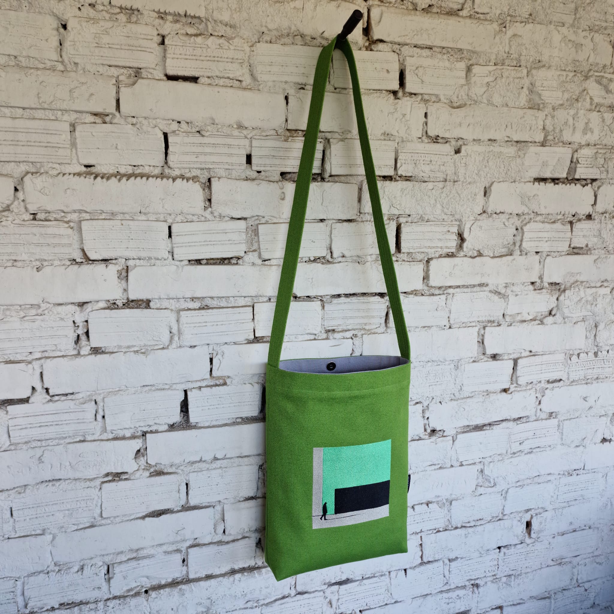 Green linen and cotton canvas crossbody bag with modern embroidery, snap button closure, and light grey lining