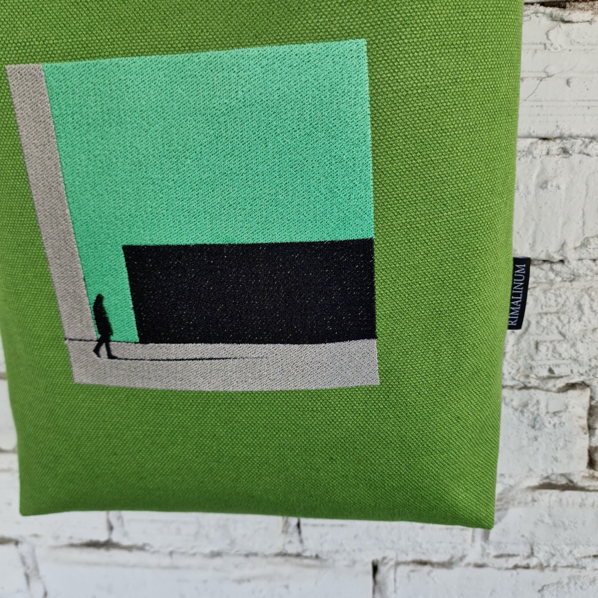 Close-up of modern embroidered design on green canvas bag with snap button closure