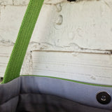 Detailed view of light grey interior lining and snap button on green crossbody bag