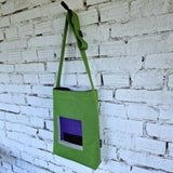 Front view of green canvas crossbody bag with purple lining and urban-inspired embroidery design