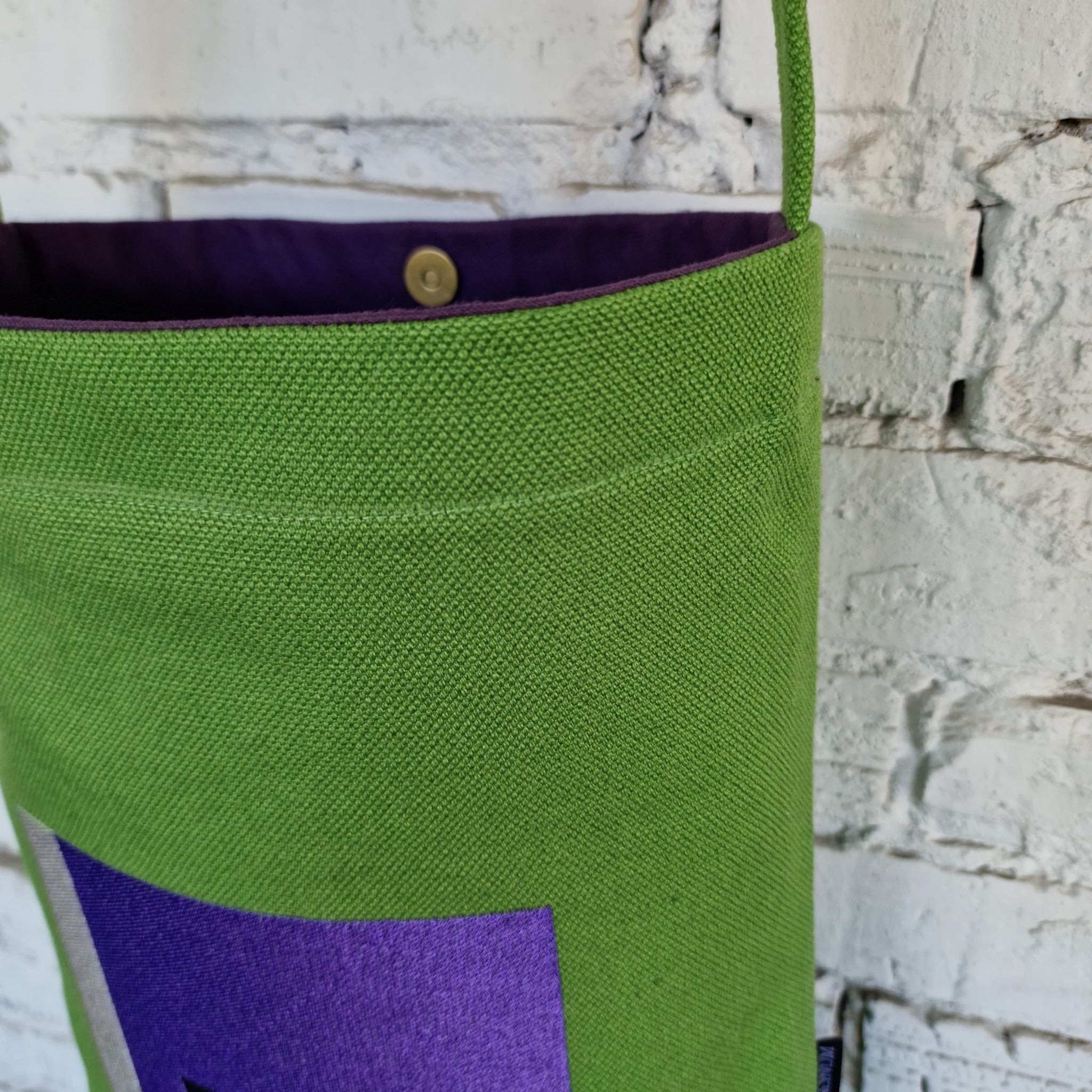 Interior view of green crossbody bag with purple lining and secure snap button closure.