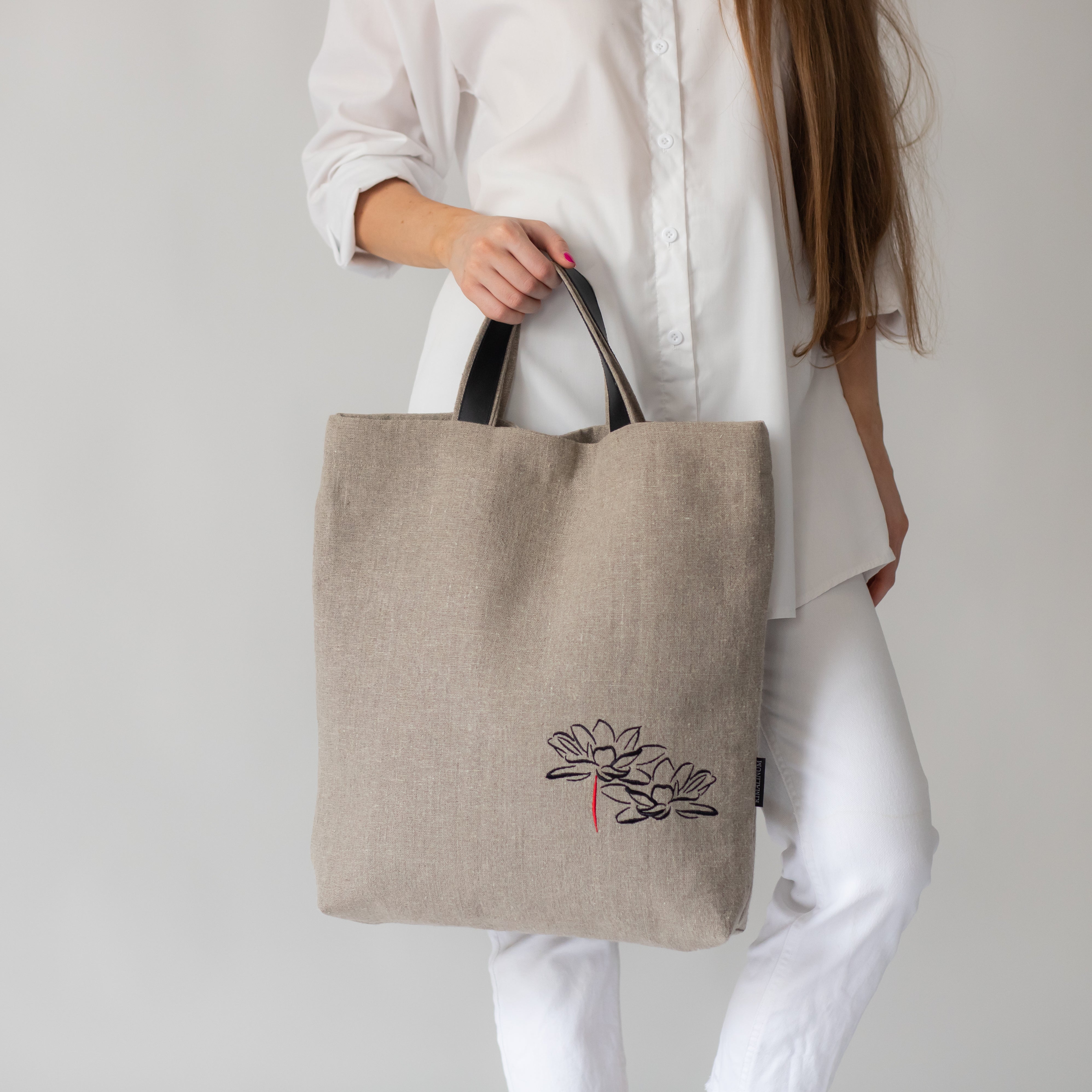 Young woman holding linen bag with embroidery of lotus flowes